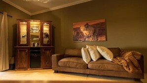 Una sala de estar con un sofá marrón, un mueble de madera y un cuadro de un guepardo.