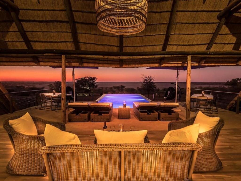 Un espacio lounge al aire libre con mobiliario de mimbre y vista a la piscina.