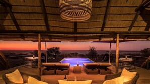 Un espacio lounge al aire libre con mobiliario de mimbre y vista a la piscina.