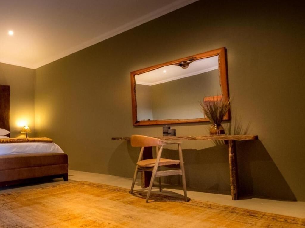 A bedroom with a bed, a desk, a chair, and a mirror.