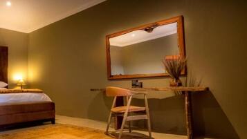 A bedroom with a bed, a desk, a chair, and a mirror.