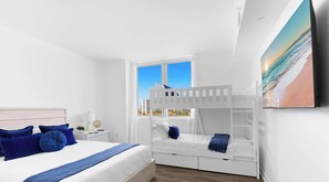 A bedroom with a bunk bed, a single bed, and a large window with a city view. - 3-BR Resort Style w/ Bay View & Private Balcony (Hallandale Beach)