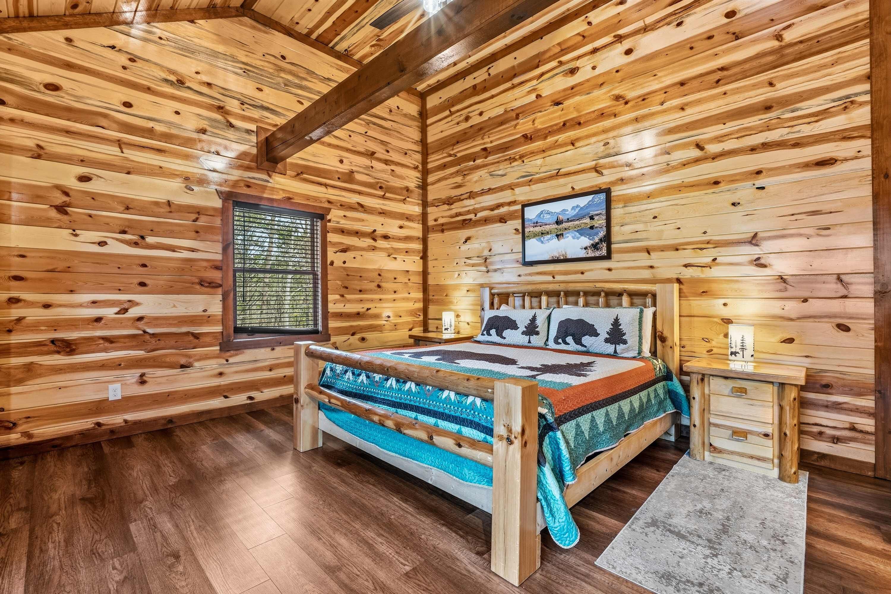 A log cabin bedroom with a bed, a window, and a painting on the wall.