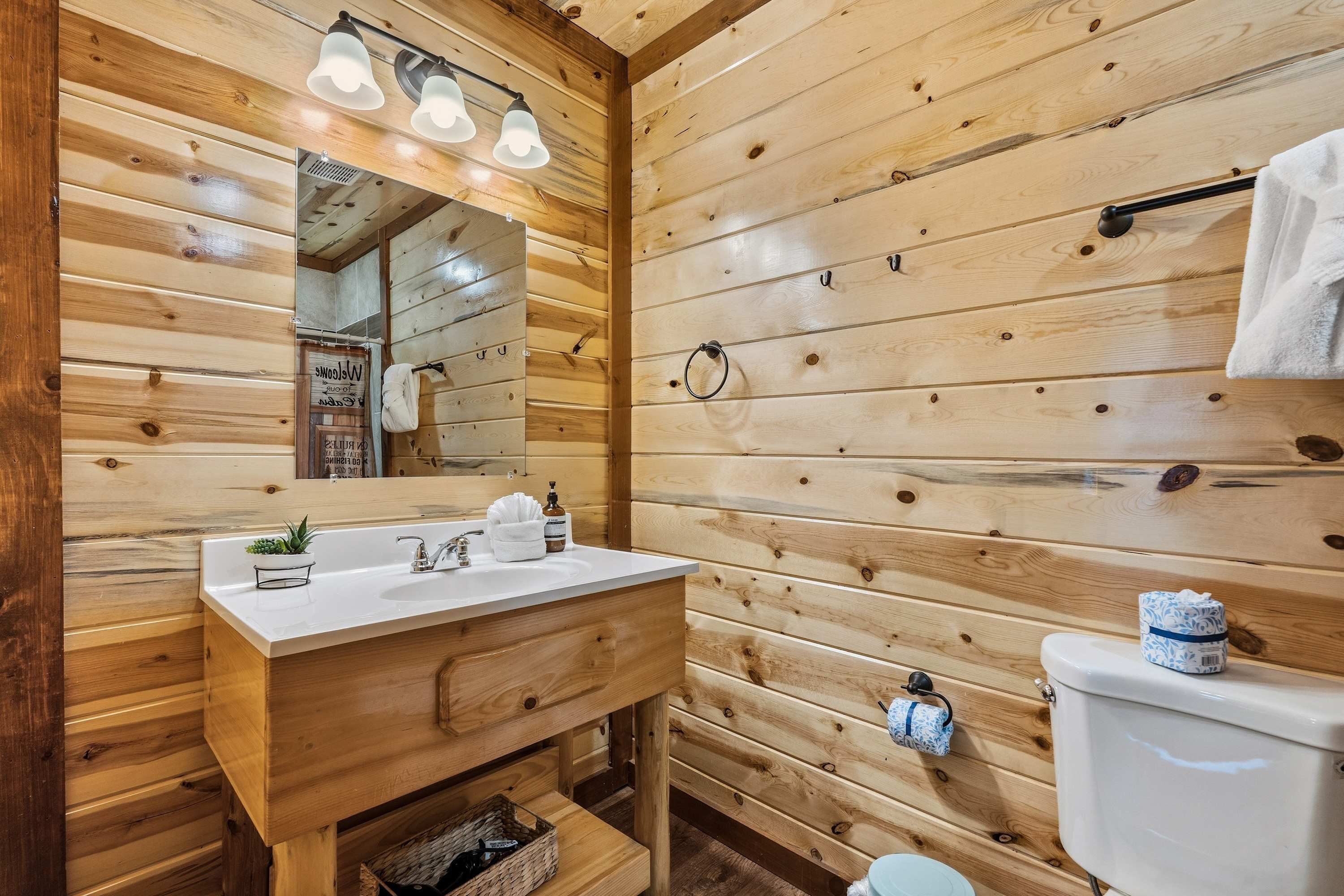 A wooden-paneled bathroom with a sink, mirror, and toilet.