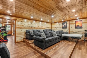 Un salon confortable avec un canapé d’angle, une petite table et une console de jeux.