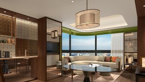Ein modernes Wohnzimmer mit einem Glastisch, einer Couch mit Kissen, einem Essbereich mit Tisch und Stühlen sowie einem großen Fenster mit Blick auf die Stadt.
