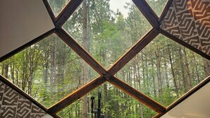 Uma banheira com vista para uma floresta através de uma estrutura de janela geométrica.