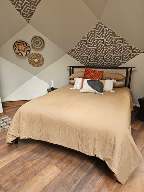 Un dormitorio con una cama grande, un cabecero y un tapiz de pared con estampado geométrico.