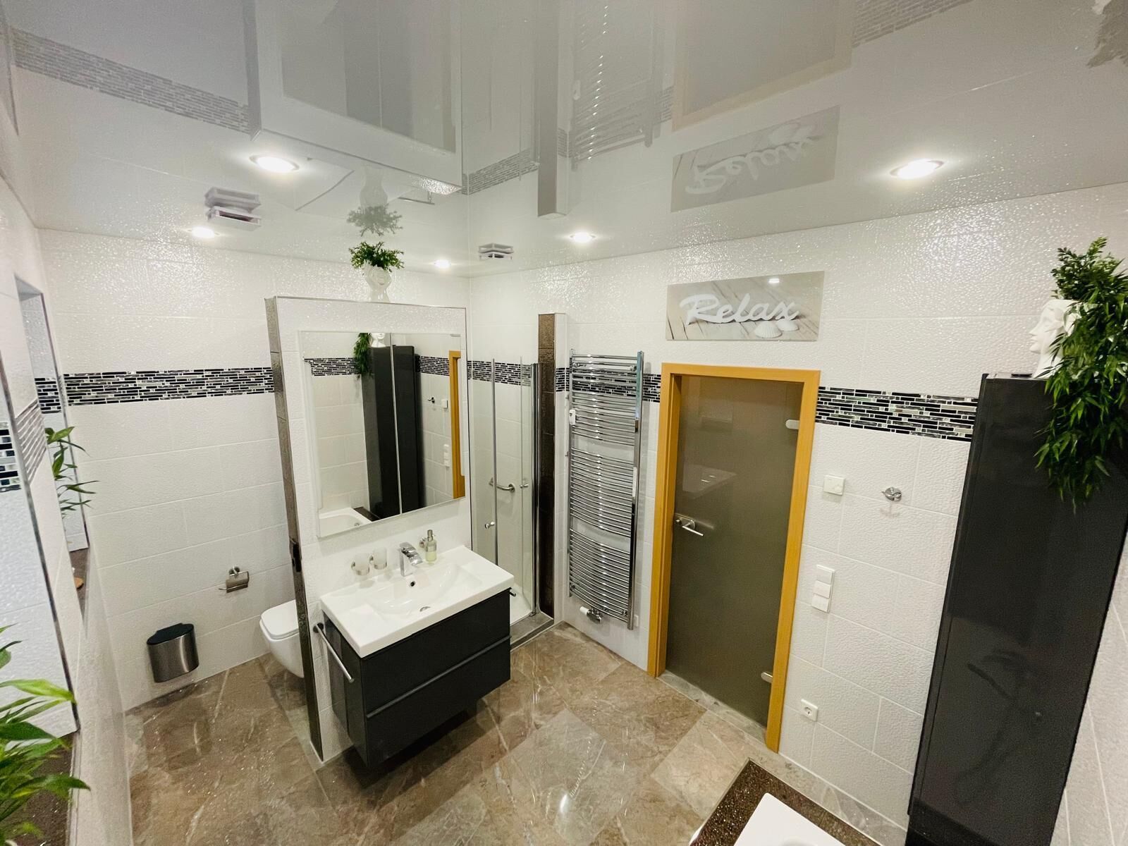Une salle de bain moderne avec un grand miroir, un lavabo, une cabine de douche et des toilettes.