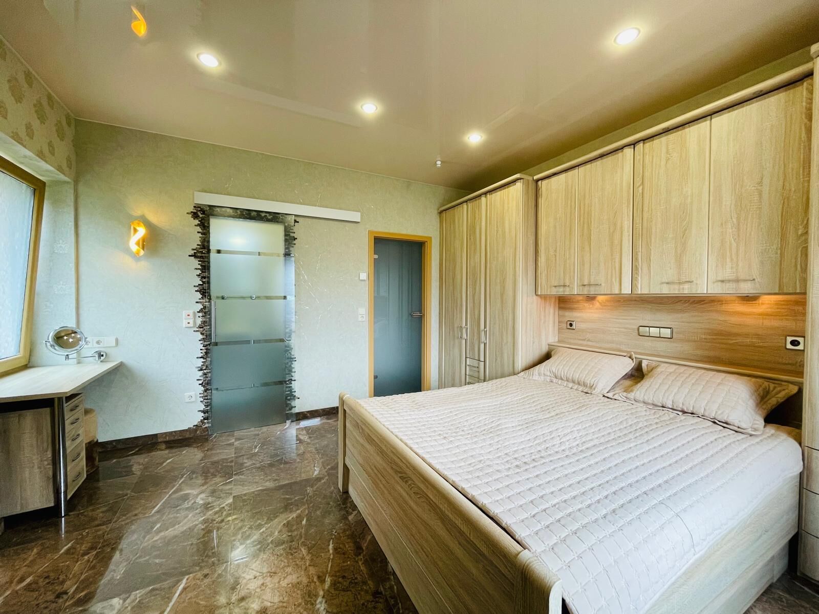 A bedroom with a bed, a desk, and a wardrobe.