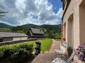 Ein Innenhof mit Backsteinmauer, einem Metallstuhl und einem Blumentopf.