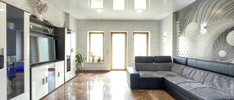 A spacious living area with a modern kitchen, a large sectional sofa, and a decorative wall.