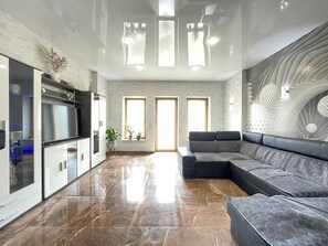 Ein geräumiges Wohnzimmer mit einer modernen Küche, einem großen Ecksofa und einer Wanddekoration.