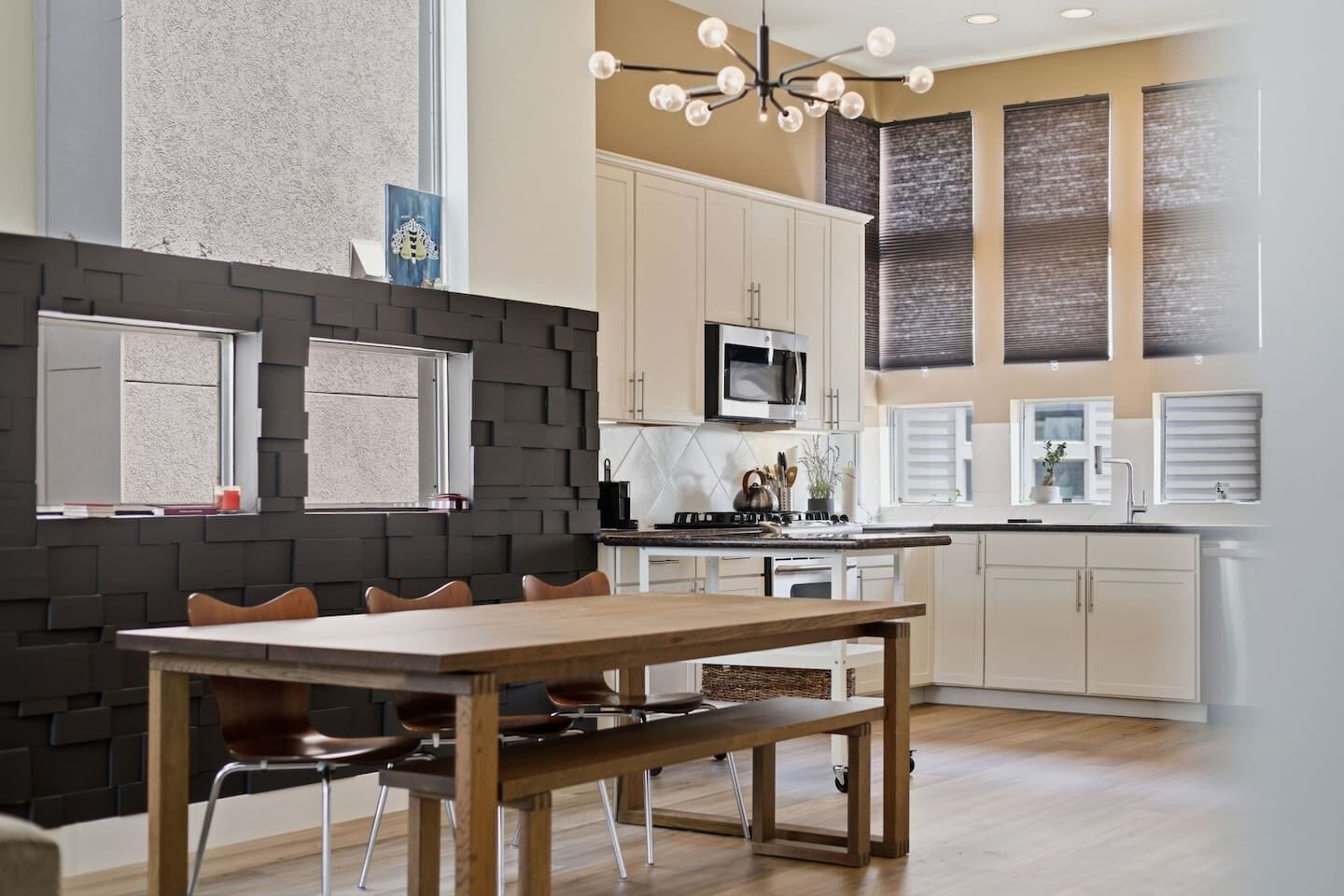 A modern kitchen with a dining area, featuring a central island, a microwave, and a stove.