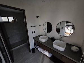 A modern bathroom with two sinks, a large mirror, and a towel rack. - Estudio a pasos de playa Santa Cruz (Bahía de Santa Cruz Huatulco)