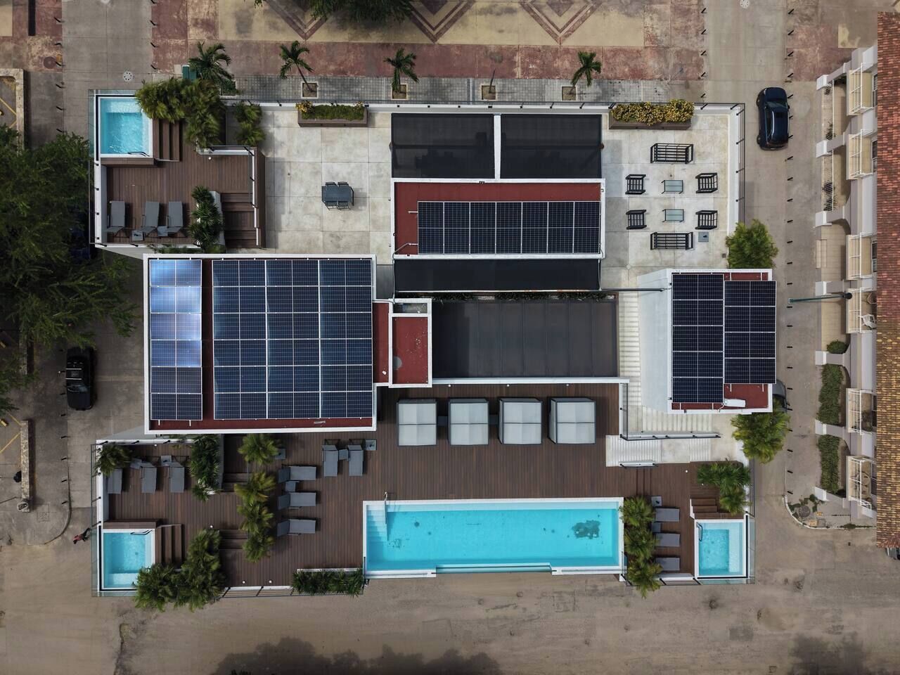 Een dak met een zwembad, zonnepanelen en terrasmeubels.