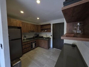 A modern kitchen with wooden cabinets, a stainless steel refrigerator, and a built-in oven. - Estudio a pasos de playa Santa Cruz (Bahía de Santa Cruz Huatulco)