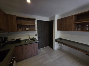 A modern kitchen with wooden cabinets, a countertop, and a door leading to another room. - Estudio a pasos de playa Santa Cruz (Bahía de Santa Cruz Huatulco)