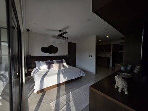 A modern bedroom with a large bed, a ceiling fan, and a view of the adjacent living area. - Estudio a pasos de playa Santa Cruz (Bahía de Santa Cruz Huatulco)