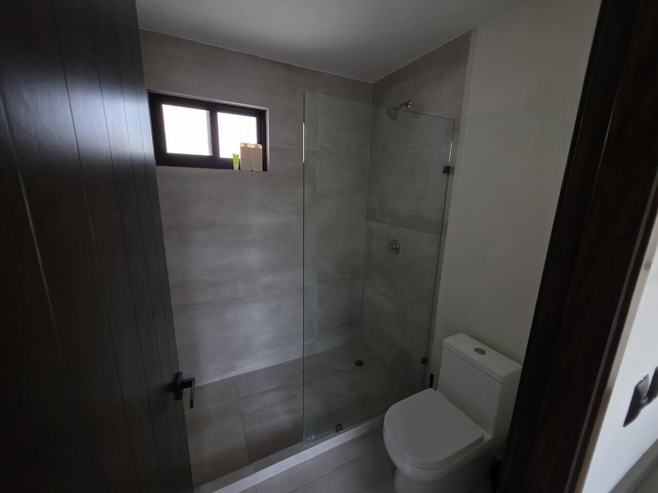 Kylpyhuoneessa on lasiseinällä varustettu suihku, wc ja ikkuna suihkun yläpuolella.