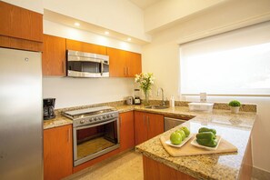 A modern kitchen with wooden cabinets, stainless steel appliances, and a granite countertop. -     Luxury 3 Bedroom Penthouse Steps from the Beach (Puerto Vallarta)