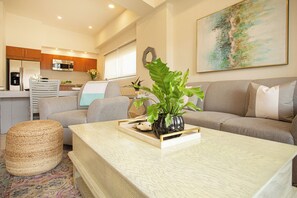 Ein modernes Wohnzimmer mit einer Couch, einem Couchtisch und einer Küche im Hintergrund.