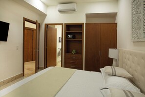 Quarto com cama, guarda-roupa, televisão e ar condicionado.