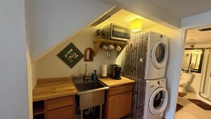 A compact kitchen with a built-in washing machine, a microwave, and a sink.