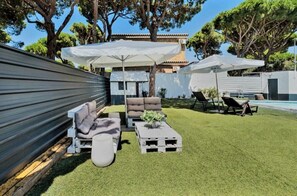 A backyard with a sofa set, two white umbrellas, a pool, and a small table. - Chalet el Molino La Barrosa: Your Getaway by the Beach in Chiclana (Chiclana de la Frontera)