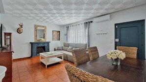 Un salon avec une cheminée, un canapé, une table basse et une table à manger avec des chaises.