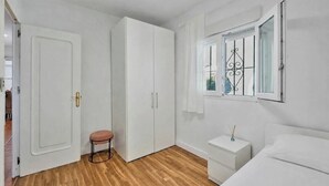 Une chambre à coucher avec un lit, une table de chevet, une armoire et une fenêtre avec un rideau.