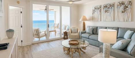 A spacious living room with a balcony, a sofa set, a coffee table, and a lamp.