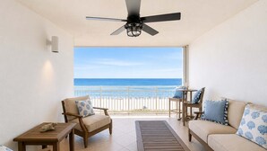Un balcone con vista sulla spiaggia, arredato con un divano, sedie e un tavolo.