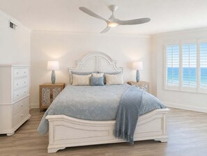 Ein Schlafzimmer mit einem großen Bett, zwei Nachttischen, einem Deckenventilator und einem Fenster mit Blick.