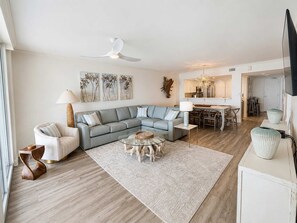 Ein modernes Wohnzimmer mit einem Ecksofa, einem Couchtisch und einem Essbereich mit Stühlen.