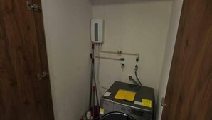 A laundry room with a washing machine, a dryer, and a utility wall with electrical outlets and a fire extinguisher. - Departamento una recámara en Santa Cruz (Bahía de Santa Cruz Huatulco)
