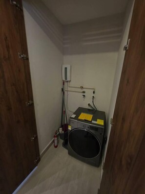 Ein Waschraum mit Waschmaschine, Trockner und einer Nebenwand mit Steckdosen und Feuerlöscher.