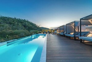 Ein Swimmingpool mit Liegestühlen und einer Holzterrasse, umgeben von viel Grün.