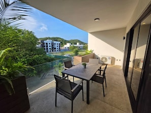 Un balcon avec une table et des chaises, une plante en pot et un appareil de climatisation.