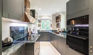 Una cocina moderna con encimera de mármol, electrodomésticos de acero inoxidable y vistas al exterior.