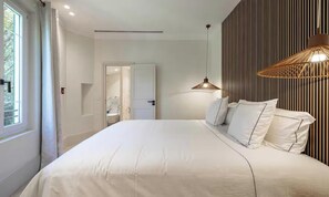 A bedroom with a large bed, a bedside lamp, and a view of a bathroom. - EXPERIENCE THE ELEGANCE OF THE FRENCH RIVIERA IN THIS EXCEPTIONAL 300 M² VILLA (Cannes)