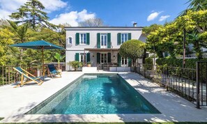 A two-story house with a swimming pool, outdoor seating, and a fenced garden area. - EXPERIENCE THE ELEGANCE OF THE FRENCH RIVIERA IN THIS EXCEPTIONAL 300 M² VILLA (Cannes)