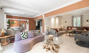 A modern living room with a curved sofa, a coffee table, and a dining area in the background. - EXPERIENCE THE ELEGANCE OF THE FRENCH RIVIERA IN THIS EXCEPTIONAL 300 M² VILLA (Cannes)