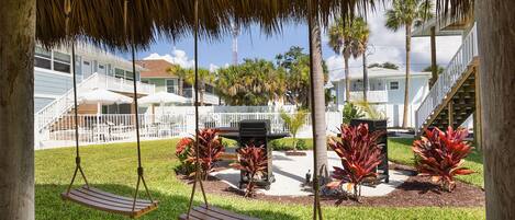 A covered outdoor area with a swing set, a grill, and a pool.