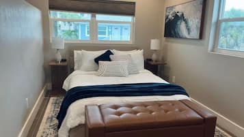 A bedroom with a bed, bedside tables, a window, and a painting on the wall.