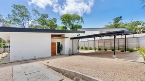 A modern house with a covered patio, a gravel driveway, and a garden with cacti. - Villa con Piscina Privada a 3 min de la Playa / Concierge incluido (Playa Grande)