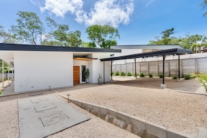 A modern house with a covered patio, a gravel driveway, and a garden with cacti. - Villa con Piscina Privada a 3 min de la Playa / Concierge incluido (Playa Grande)