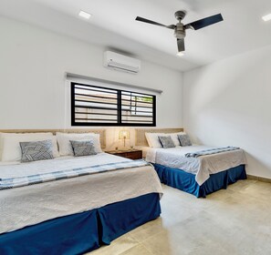 Slaapkamer met twee bedden, een plafondventilator, een airconditioning en een raam met uitzicht.