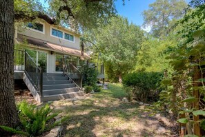 A two-story house with a covered porch and a staircase leading to the entrance. - 5 bed/5 bath Hiking on Greenbelt Close to Zilker! (Austin)