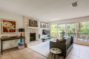 A living room with a stone fireplace, a sofa, a coffee table, and a TV. - 5 bed/5 bath Hiking on Greenbelt Close to Zilker! (Austin)